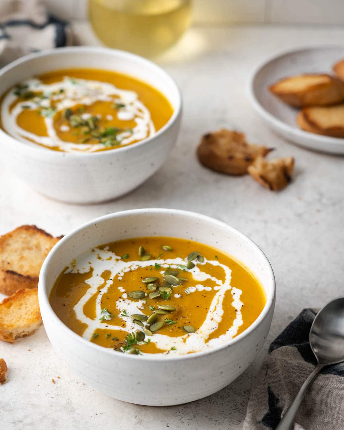 soup in a white bowl garnished with cream and pepitas