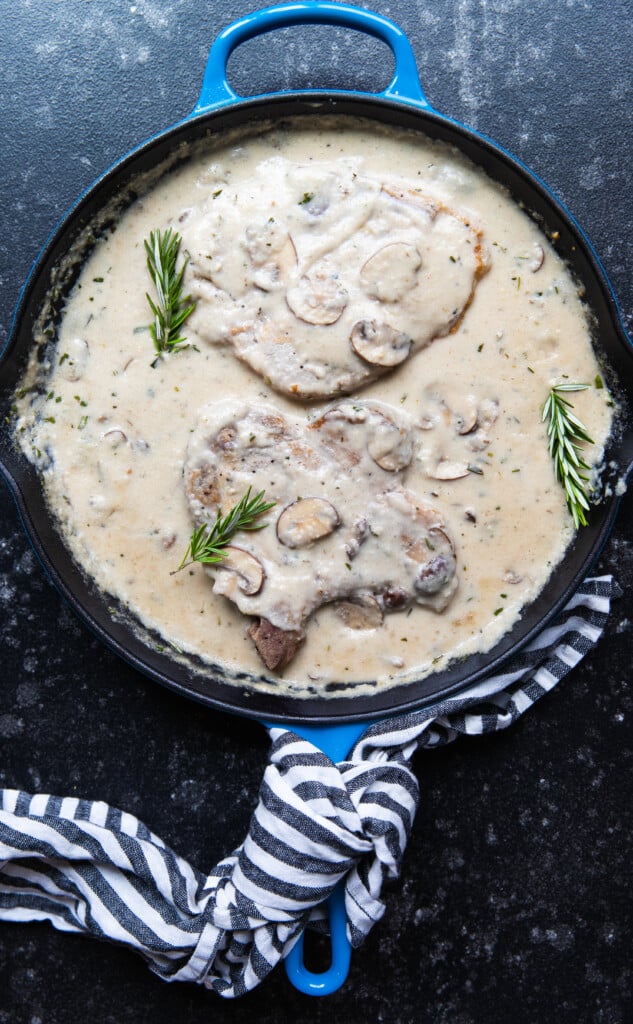 pork chops in a frying pan with mushroom gravy