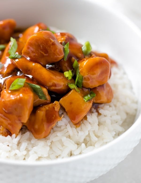 chicken with sauce on top of rice in a white bowl